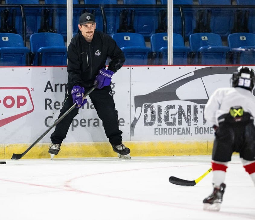 Coach Kevin Davis passing a puck to a player during a skills session